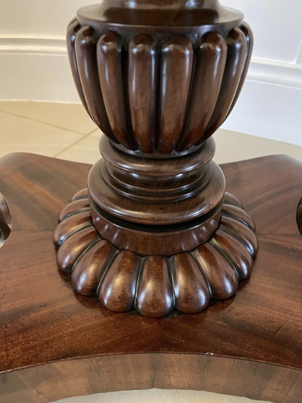 A William IV mahogany fold-over tea table with a turned gadrooned pedestal stem and a concave quadform base ending in scroll feet. View V