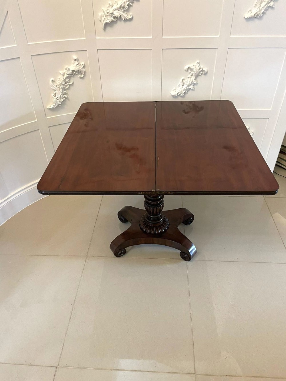 A William IV mahogany fold-over tea table with a turned gadrooned pedestal stem and a concave quadform base ending in scroll feet. View VI
