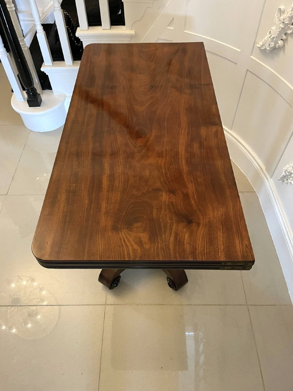 A William IV mahogany fold-over tea table with a turned gadrooned pedestal stem and a concave quadform base ending in scroll feet. View VII