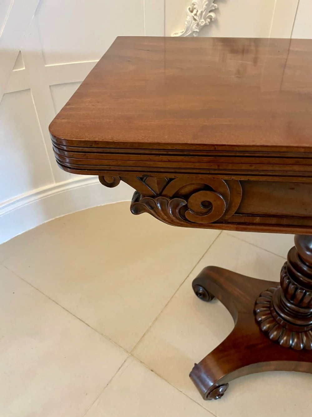 A William IV mahogany fold-over tea table with a turned gadrooned pedestal stem and a concave quadform base ending in scroll feet. View X