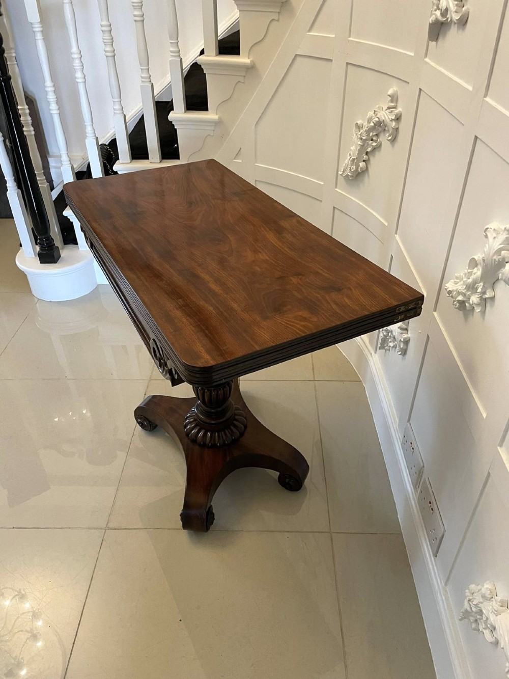 A William IV mahogany fold-over tea table with a turned gadrooned pedestal stem and a concave quadform base ending in scroll feet. View XI