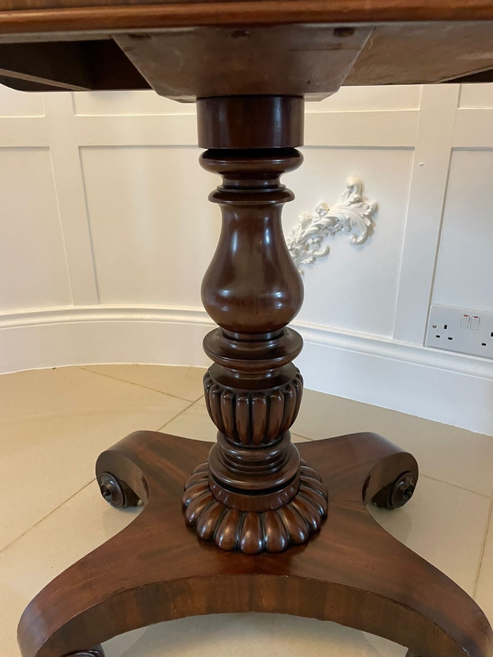 A William IV mahogany fold-over tea table with a turned gadrooned pedestal stem and a concave quadform base ending in scroll feet. View XIV