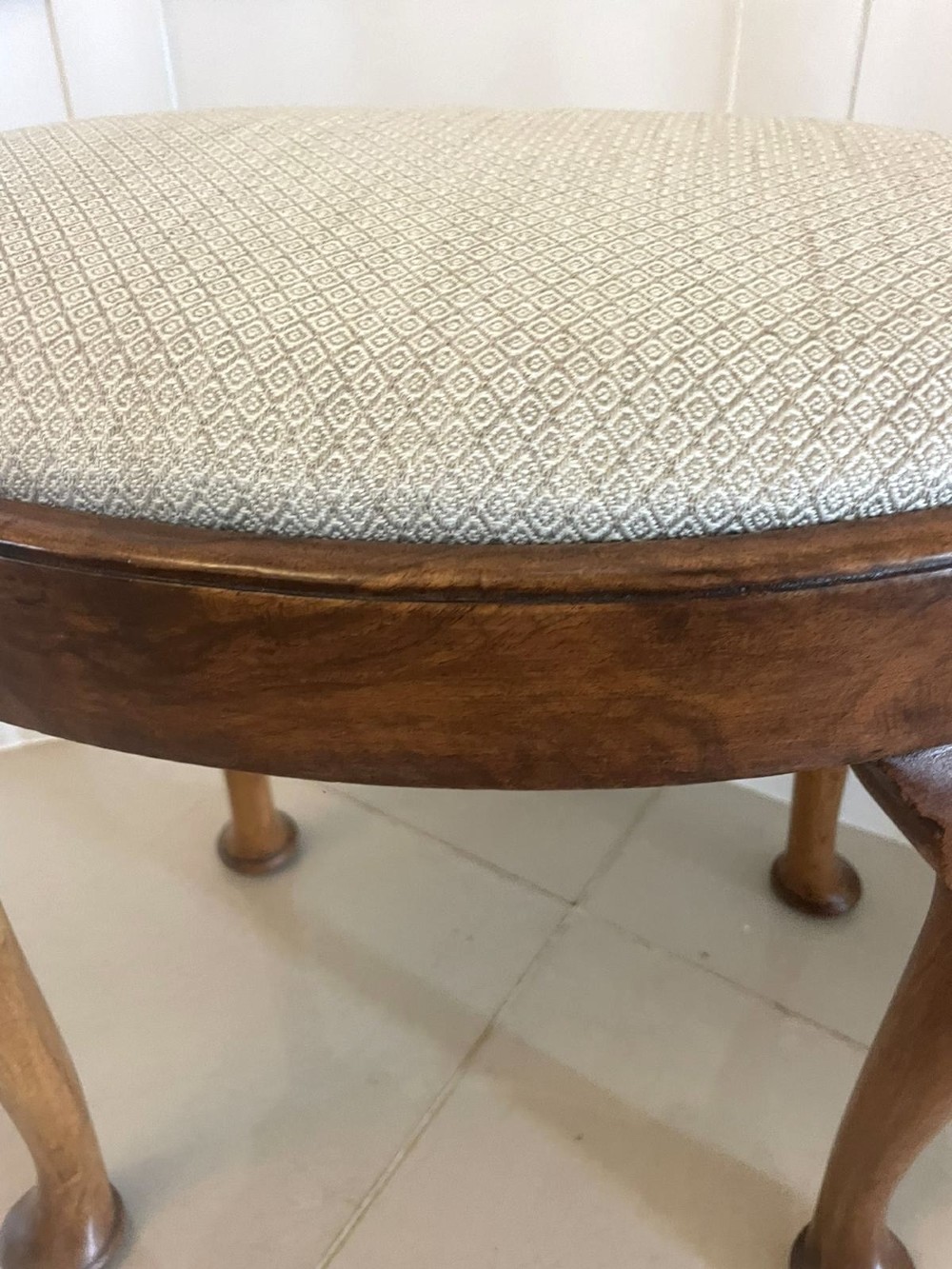 An antique oval walnut stool featuring shell-carved cabriole legs, pad feet, and a geometric pattern upholstered seat. View III