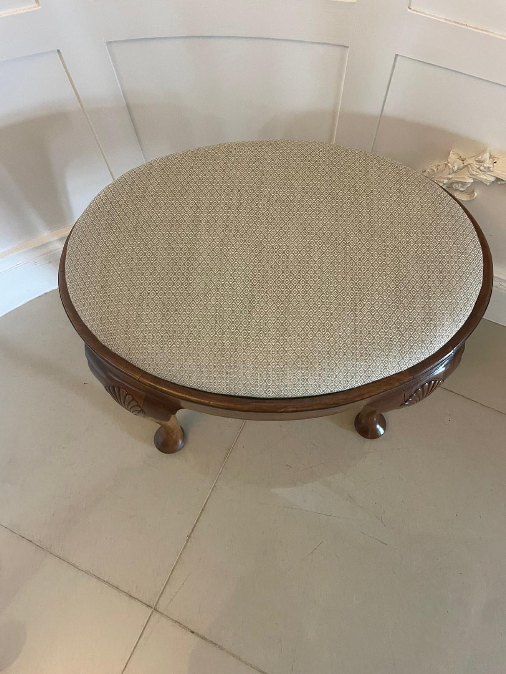 An antique oval walnut stool featuring shell-carved cabriole legs, pad feet, and a geometric pattern upholstered seat. View V