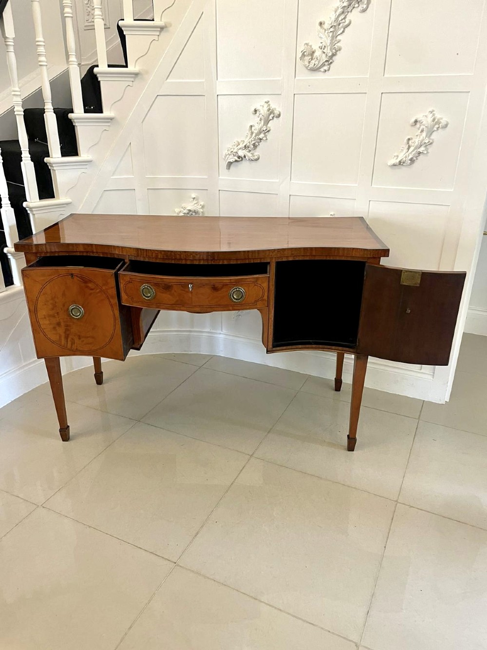 An antique satinwood serpentine-front sideboard featuring oval inlay panels, brass ring handles, and tapered square legs. View II