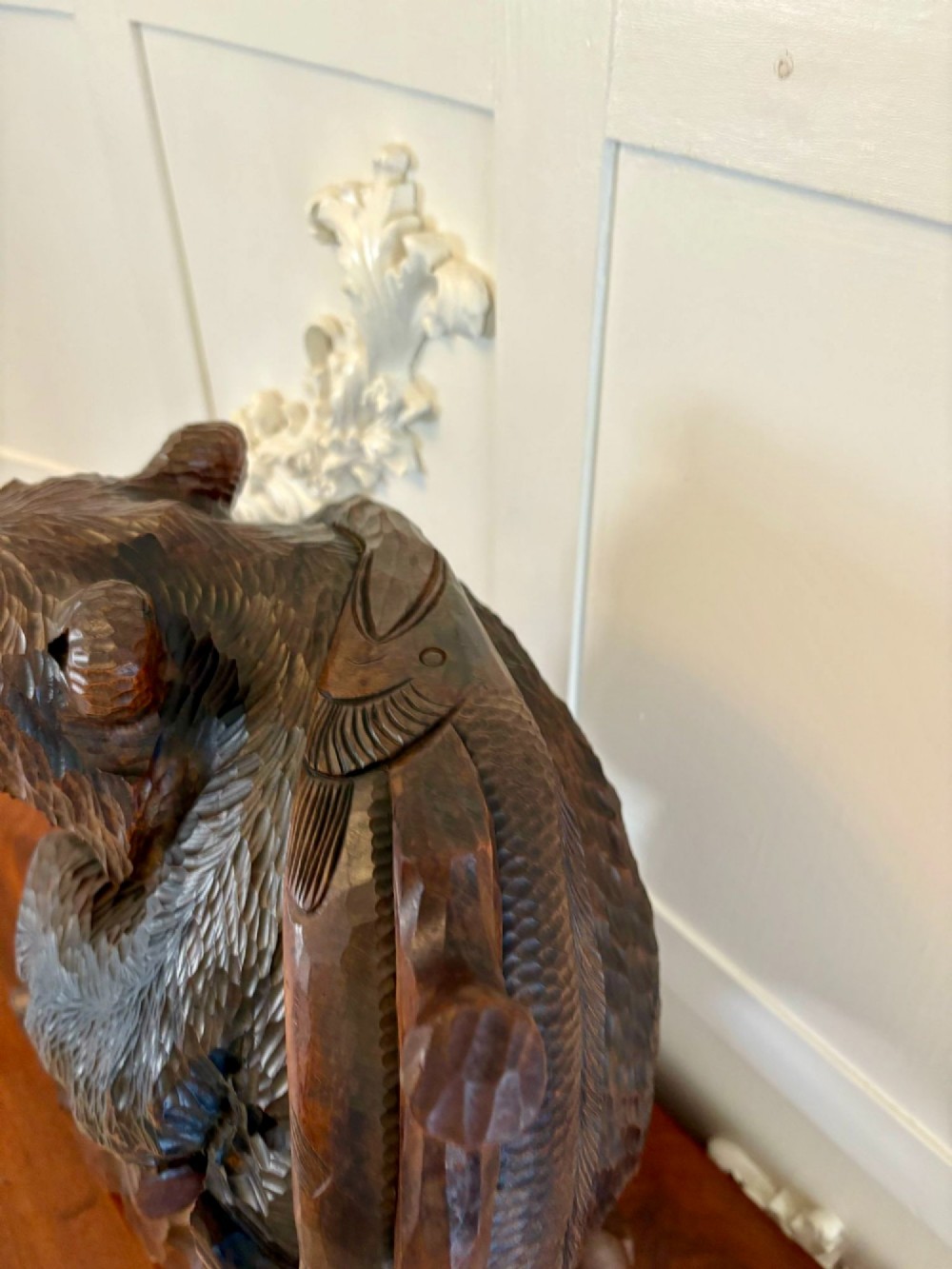 A hand-carved dark linden wood sculpture depicting a roaring bear carrying a fish over its back, positioned on a carved textured base. View V