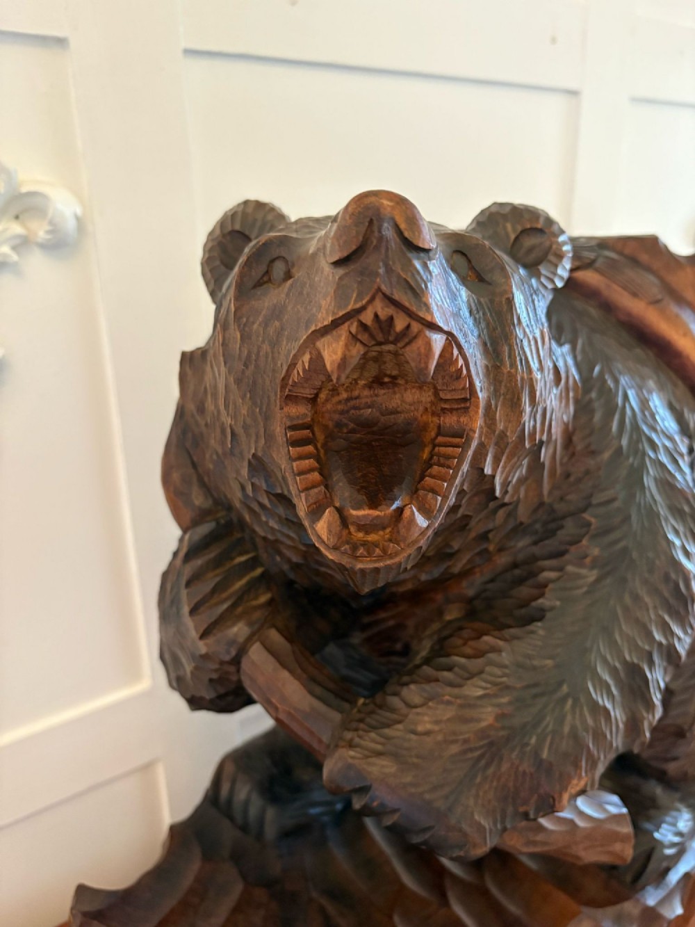 A hand-carved dark linden wood sculpture depicting a roaring bear carrying a fish over its back, positioned on a carved textured base. View VI