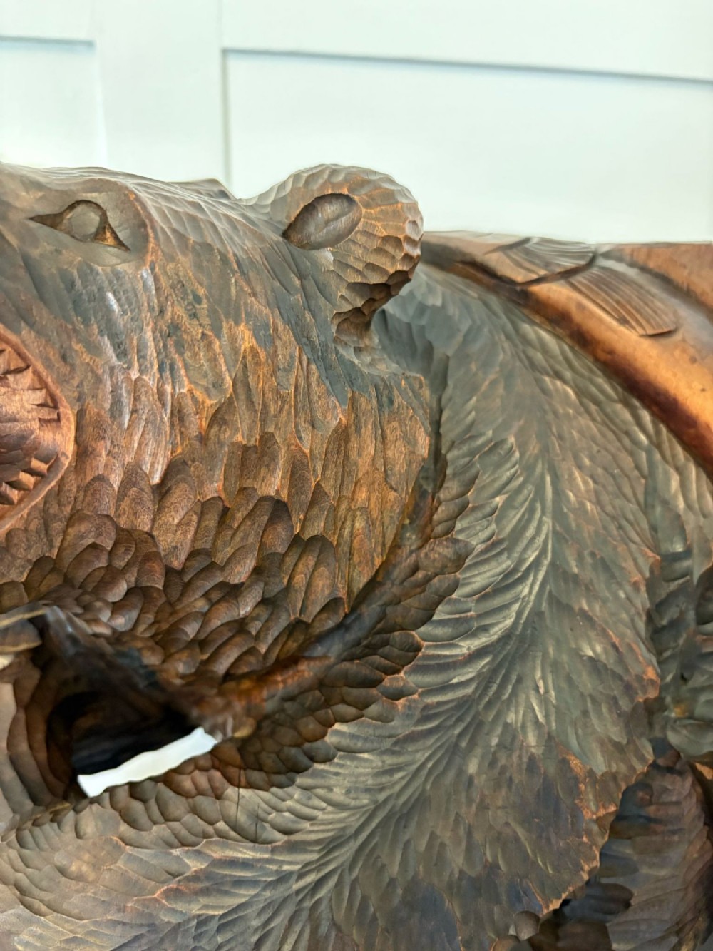 A hand-carved dark linden wood sculpture depicting a roaring bear carrying a fish over its back, positioned on a carved textured base. View VIII
