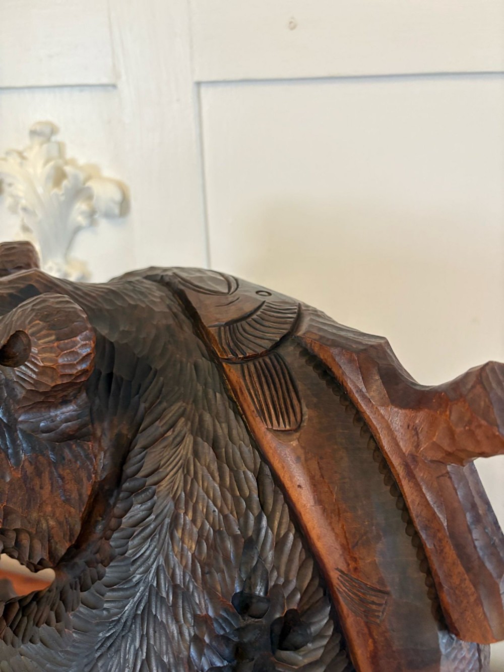 A hand-carved dark linden wood sculpture depicting a roaring bear carrying a fish over its back, positioned on a carved textured base. View XI