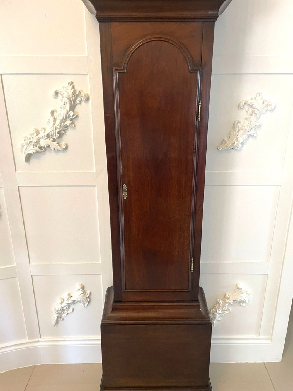 A George III mahogany longcase clock featuring an arched brass dial, urn finials, and an arched trunk door. View IX