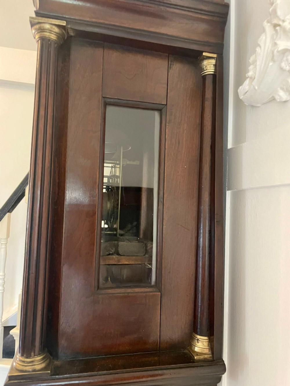 A George III mahogany longcase clock featuring an arched brass dial, urn finials, and an arched trunk door. View X