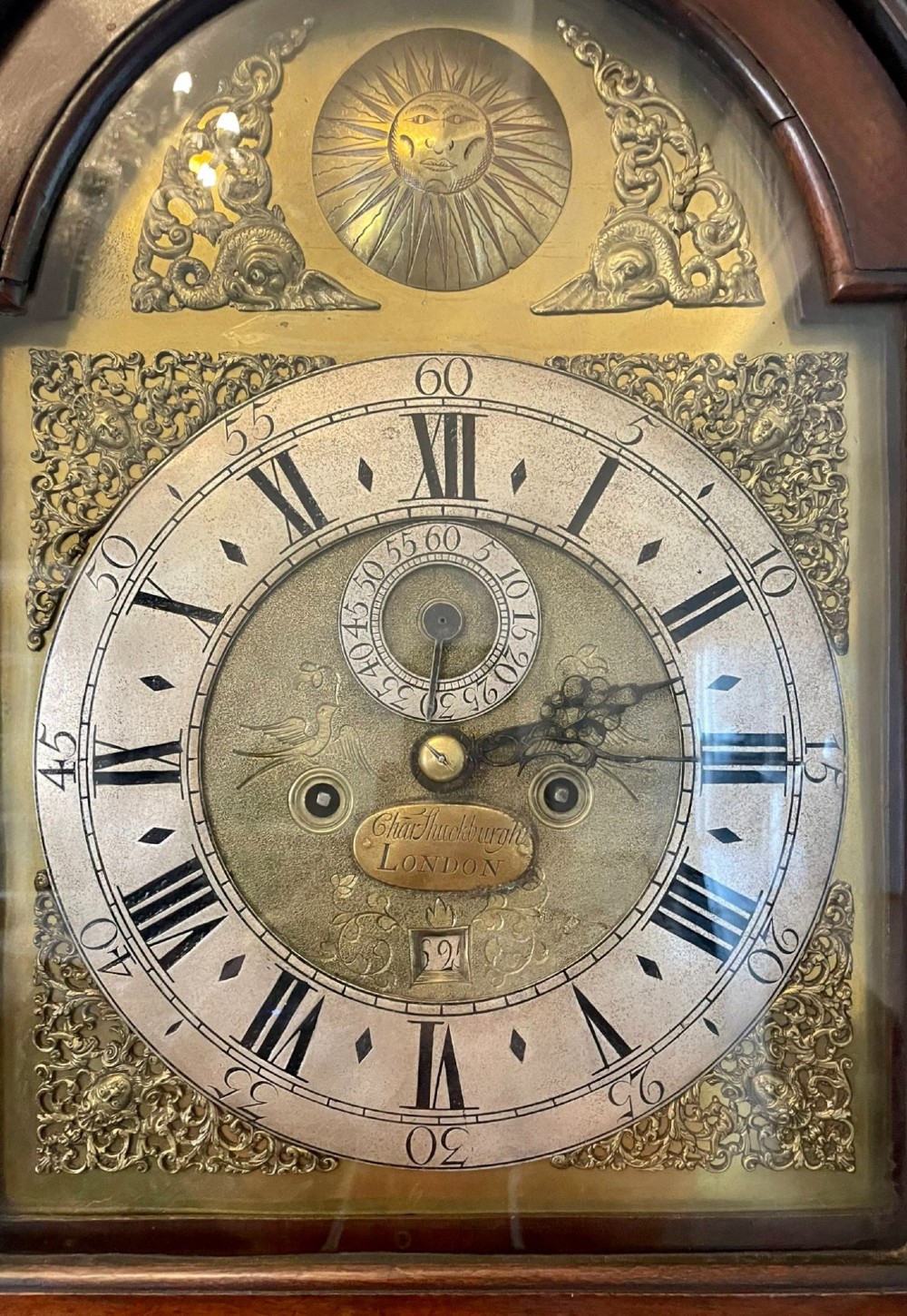 A George III mahogany longcase clock featuring an arched brass dial, urn finials, and an arched trunk door. View XIII
