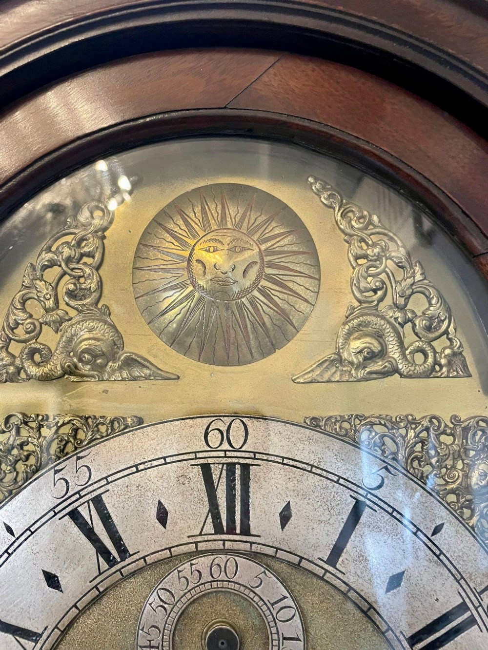 A George III mahogany longcase clock featuring an arched brass dial, urn finials, and an arched trunk door. View XIV