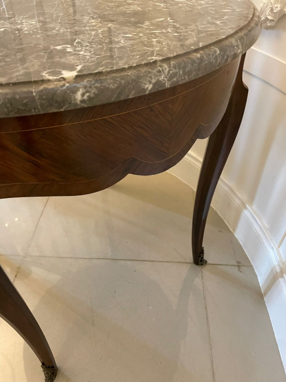 A circular French centre table with a grey marble top, kingwood veneered apron, metal mount, and curved cabriole legs. View III