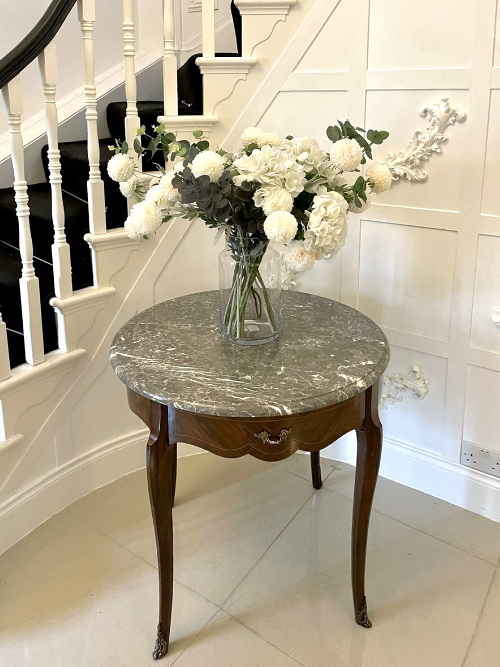 A circular French centre table with a grey marble top, kingwood veneered apron, metal mount, and curved cabriole legs. View VI