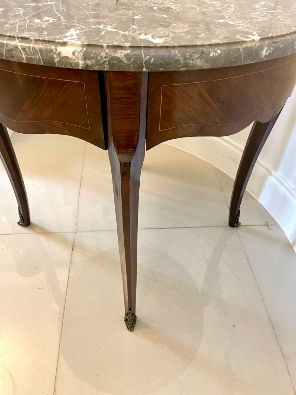 A circular French centre table with a grey marble top, kingwood veneered apron, metal mount, and curved cabriole legs. View VII