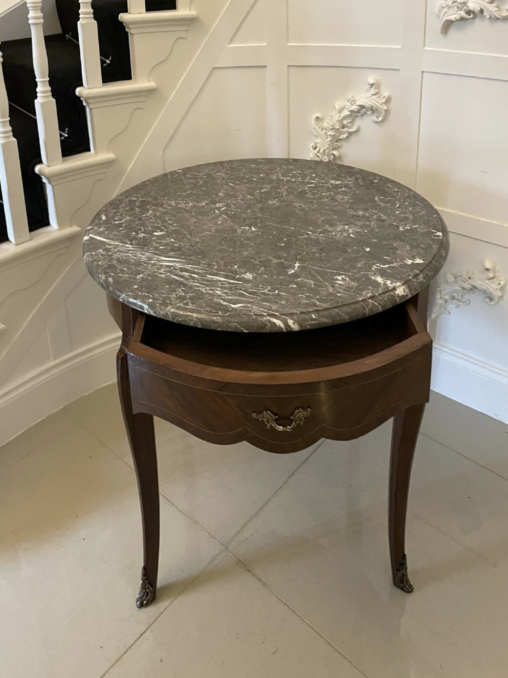 A circular French centre table with a grey marble top, kingwood veneered apron, metal mount, and curved cabriole legs. View IX