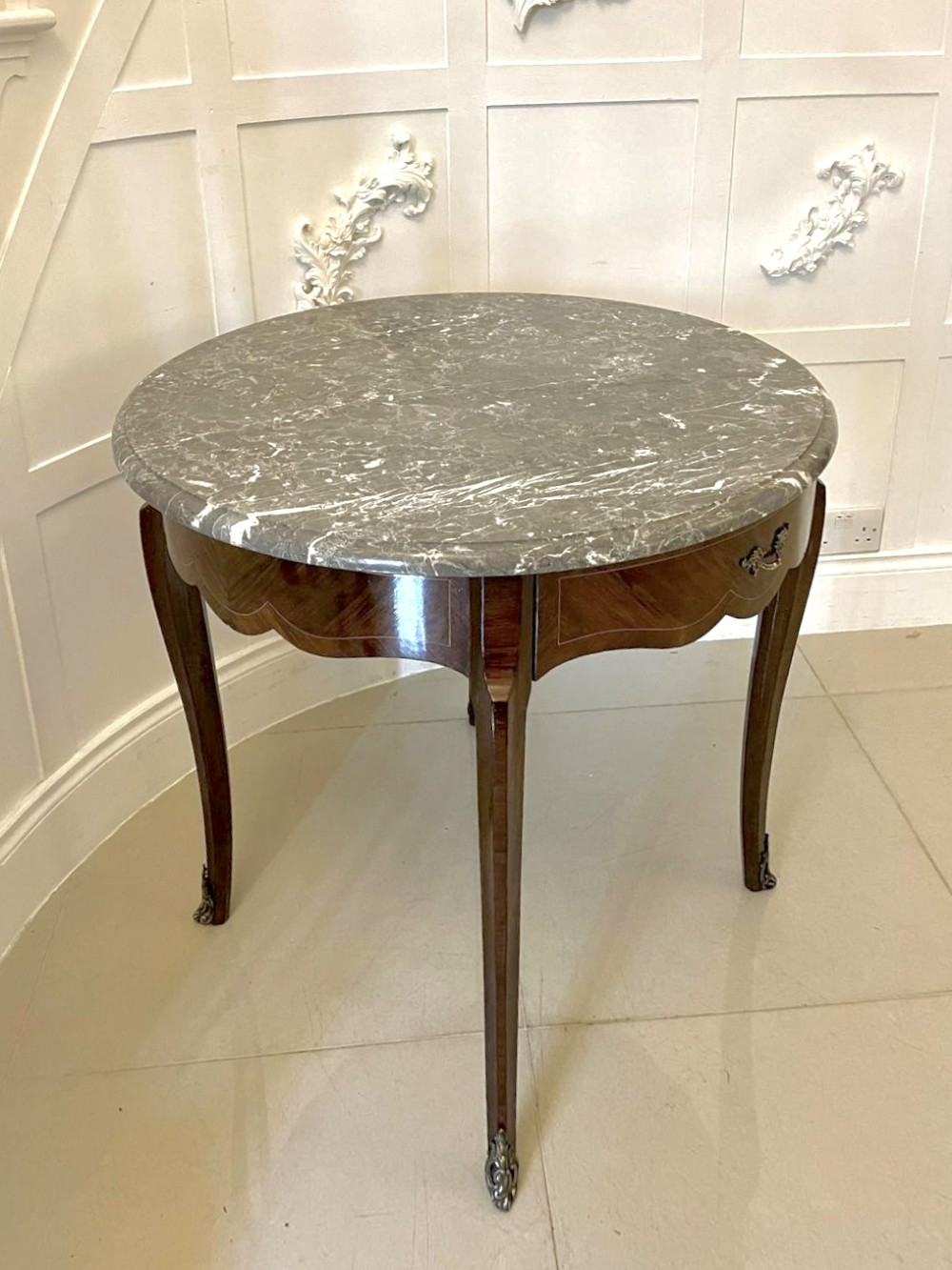 A circular French centre table with a grey marble top, kingwood veneered apron, metal mount, and curved cabriole legs. View X