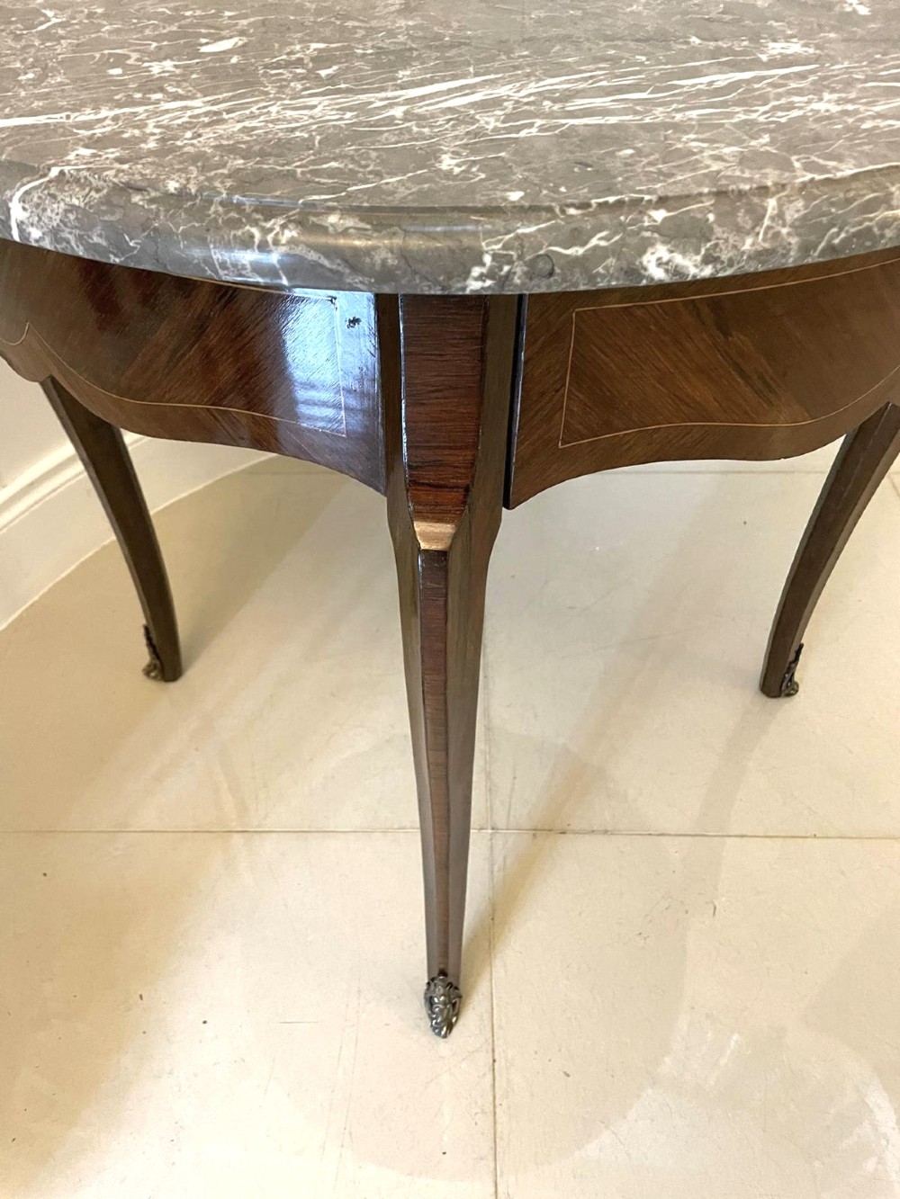A circular French centre table with a grey marble top, kingwood veneered apron, metal mount, and curved cabriole legs. View XII