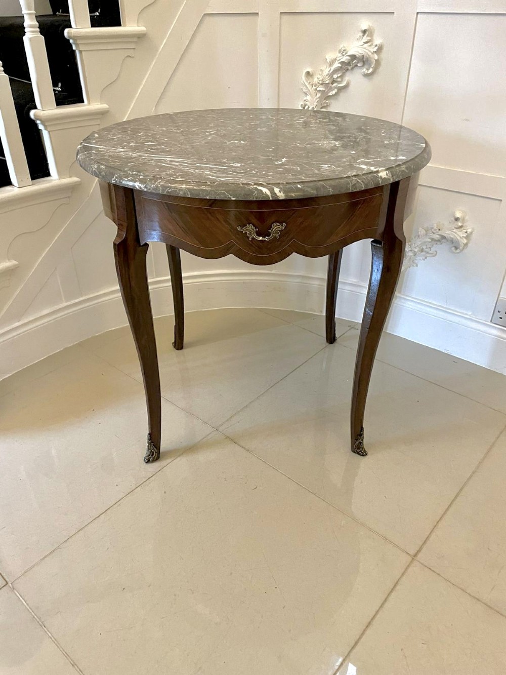 A circular French centre table with a grey marble top, kingwood veneered apron, metal mount, and curved cabriole legs. View XIII