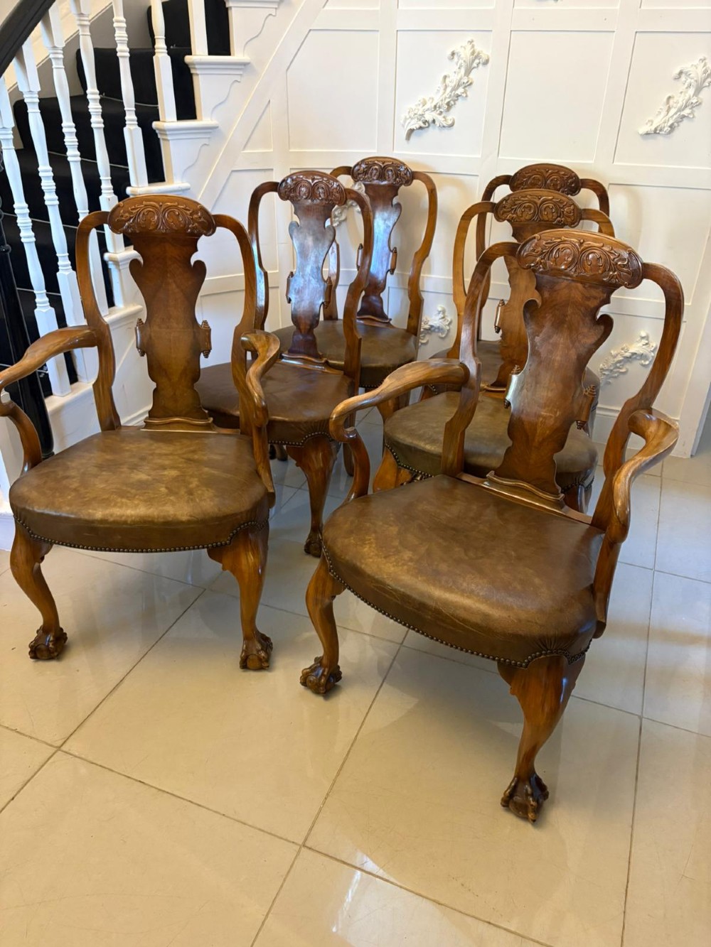 A set of six carved walnut dining chairs featuring decorative back splats, leather seats with brass studs, cabriole legs, and ball and claw feet. View II