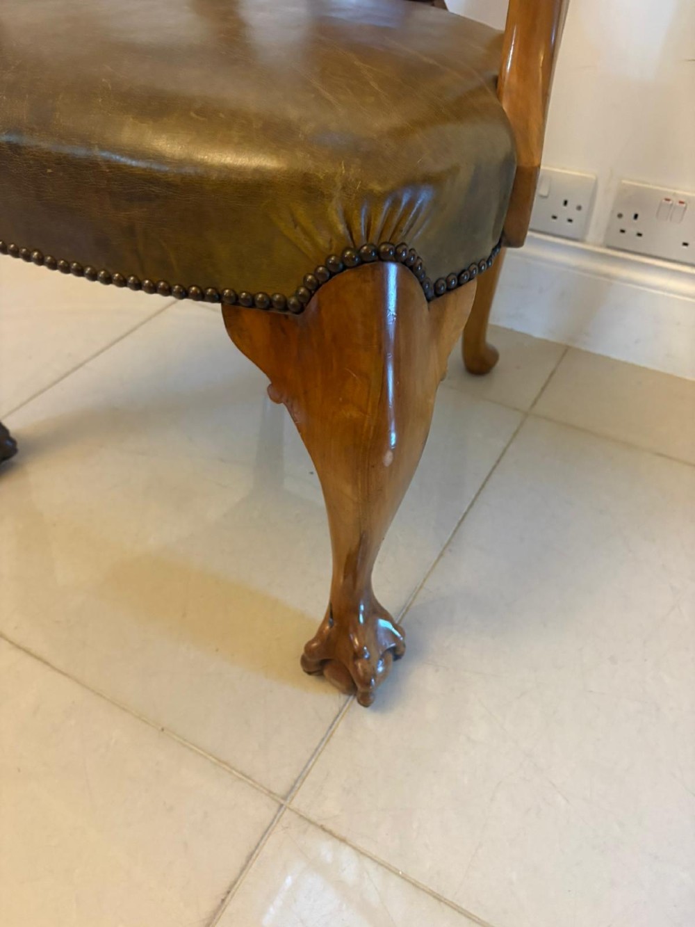 A set of six carved walnut dining chairs featuring decorative back splats, leather seats with brass studs, cabriole legs, and ball and claw feet. View III