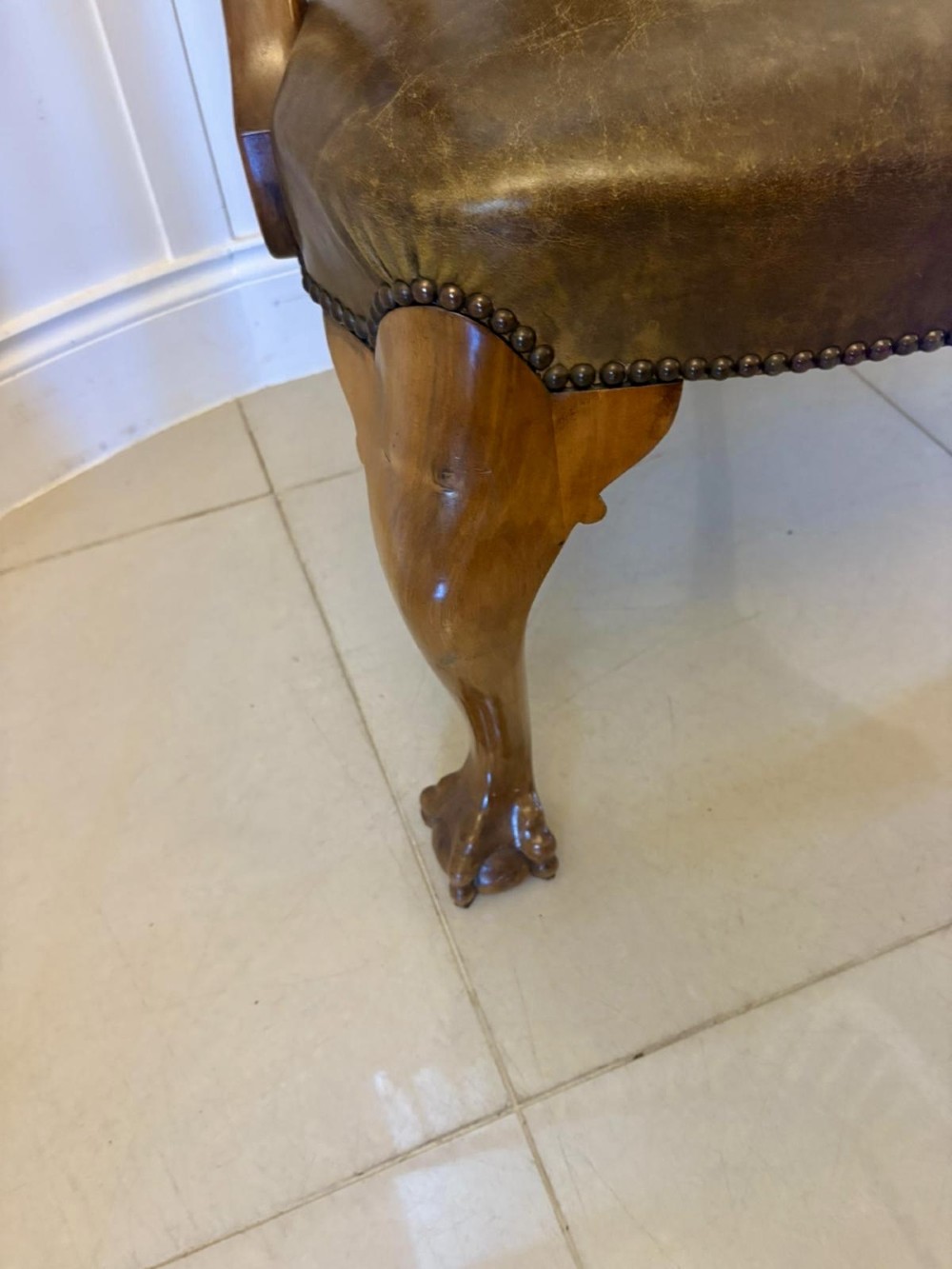 A set of six carved walnut dining chairs featuring decorative back splats, leather seats with brass studs, cabriole legs, and ball and claw feet. View V