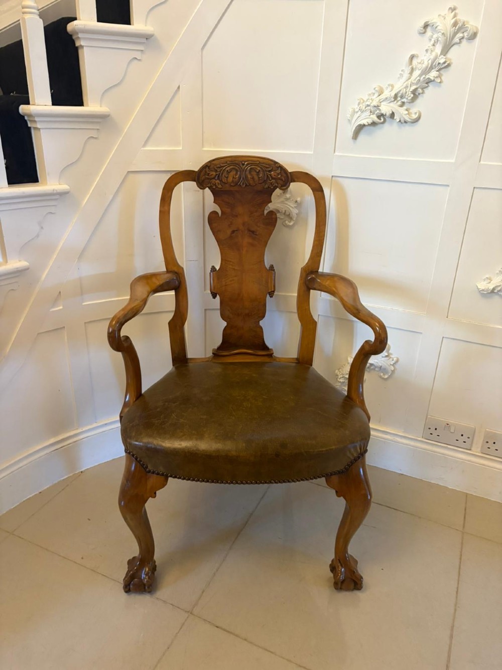 A set of six carved walnut dining chairs featuring decorative back splats, leather seats with brass studs, cabriole legs, and ball and claw feet. View VI