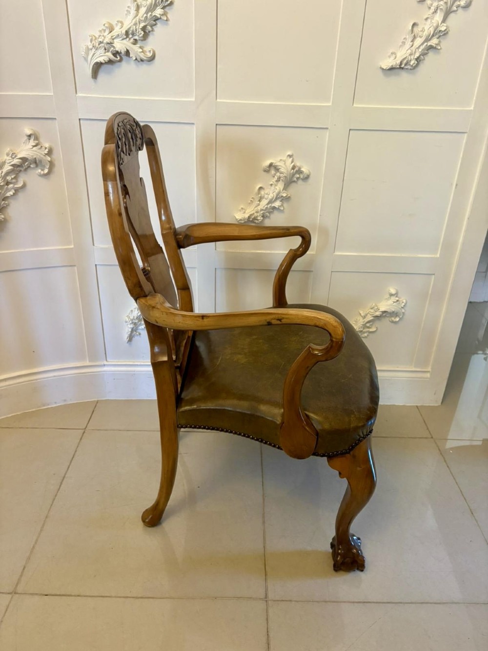 A set of six carved walnut dining chairs featuring decorative back splats, leather seats with brass studs, cabriole legs, and ball and claw feet. View VIII