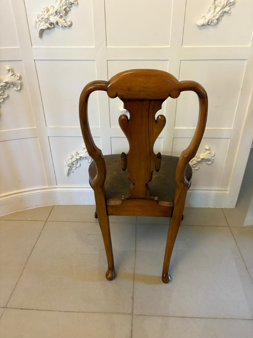 A set of six carved walnut dining chairs featuring decorative back splats, leather seats with brass studs, cabriole legs, and ball and claw feet. View X