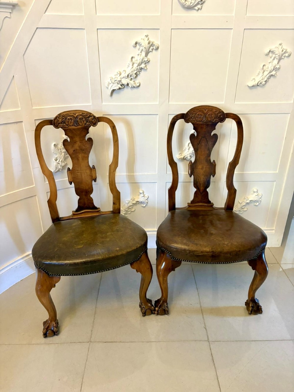 A set of six carved walnut dining chairs featuring decorative back splats, leather seats with brass studs, cabriole legs, and ball and claw feet. View XV