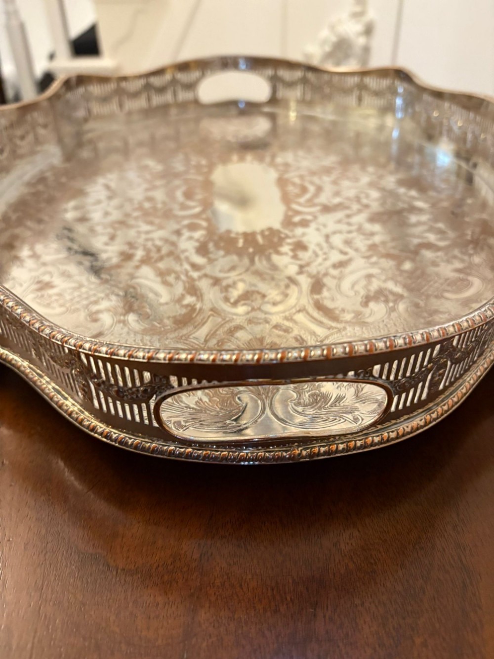 A silver-plated Edwardian tea tray featuring an engraved surface, a pierced gallery border with integrated handles, and cast feet. View II
