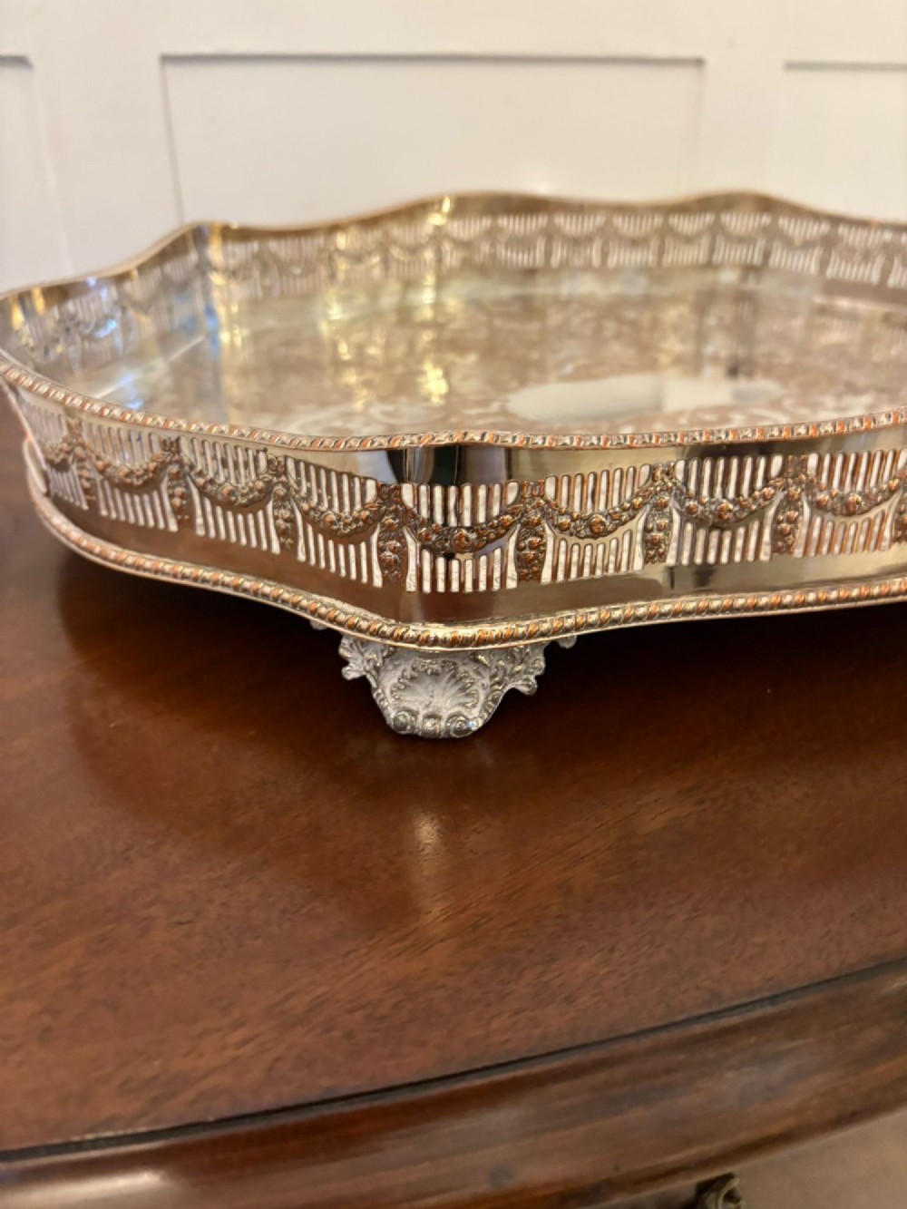 A silver-plated Edwardian tea tray featuring an engraved surface, a pierced gallery border with integrated handles, and cast feet. View III