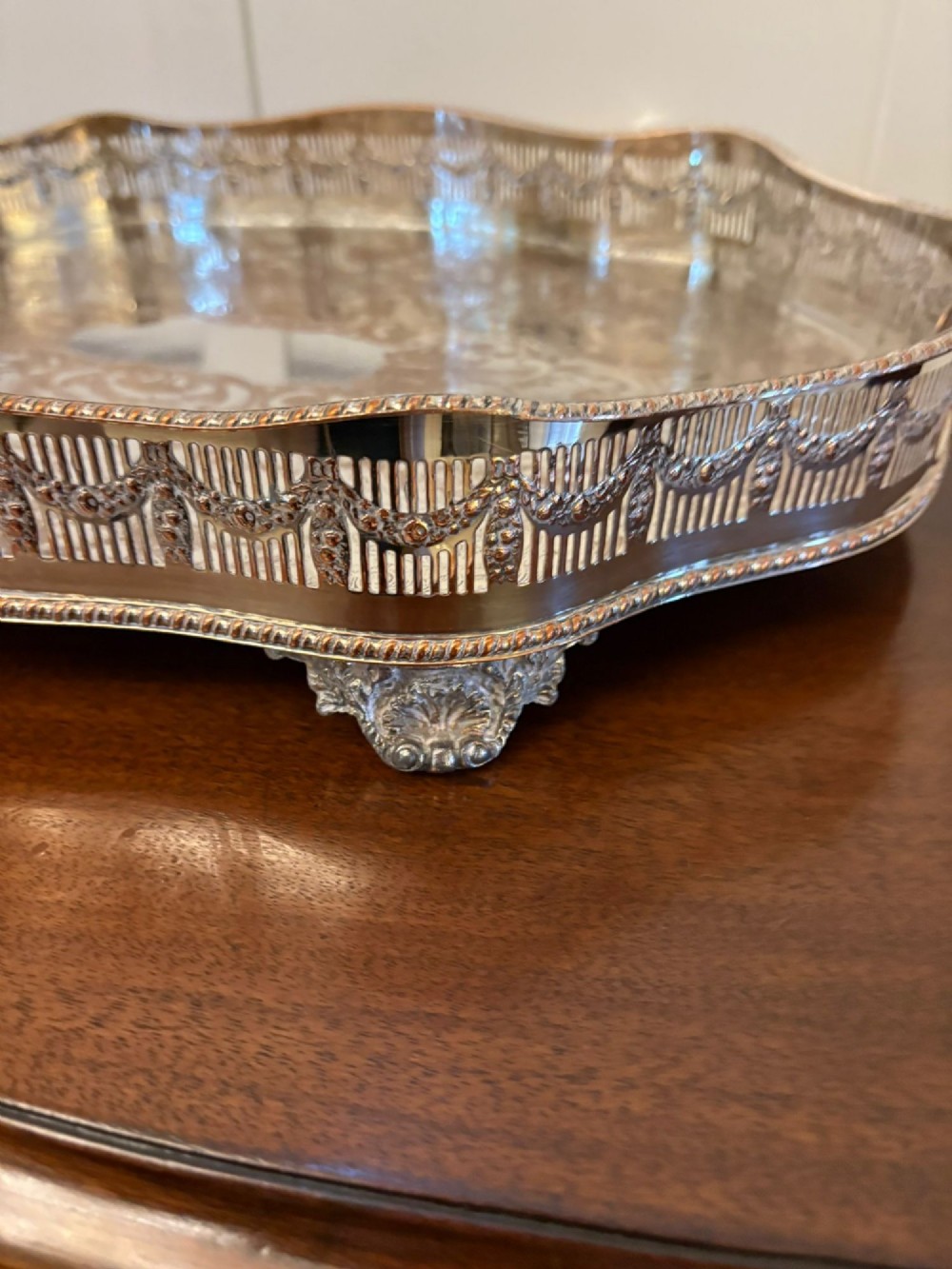 A silver-plated Edwardian tea tray featuring an engraved surface, a pierced gallery border with integrated handles, and cast feet. View V