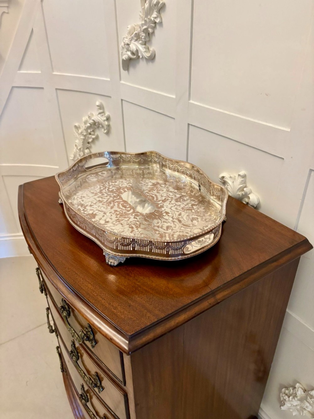 A silver-plated Edwardian tea tray featuring an engraved surface, a pierced gallery border with integrated handles, and cast feet. View VII