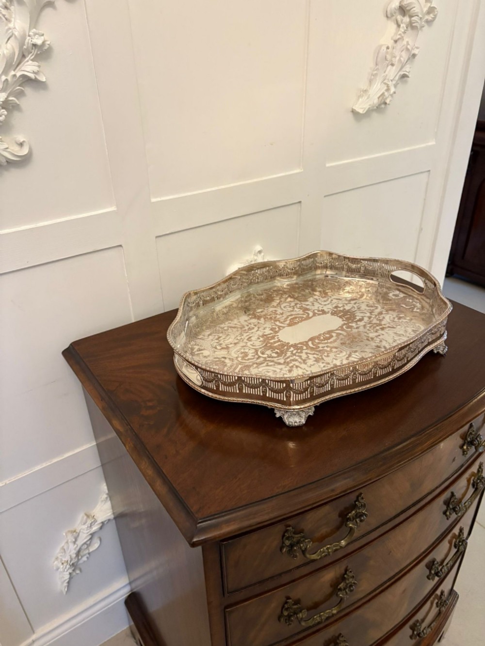 A silver-plated Edwardian tea tray featuring an engraved surface, a pierced gallery border with integrated handles, and cast feet. View VIII