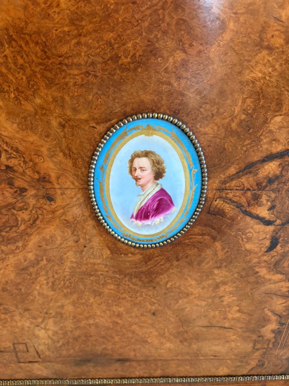 A Victorian burr walnut credenza featuring a central door with a hand-painted porcelain portrait plaque flanked by two curved glass display cupboards and gilt-brass mounts. View VI