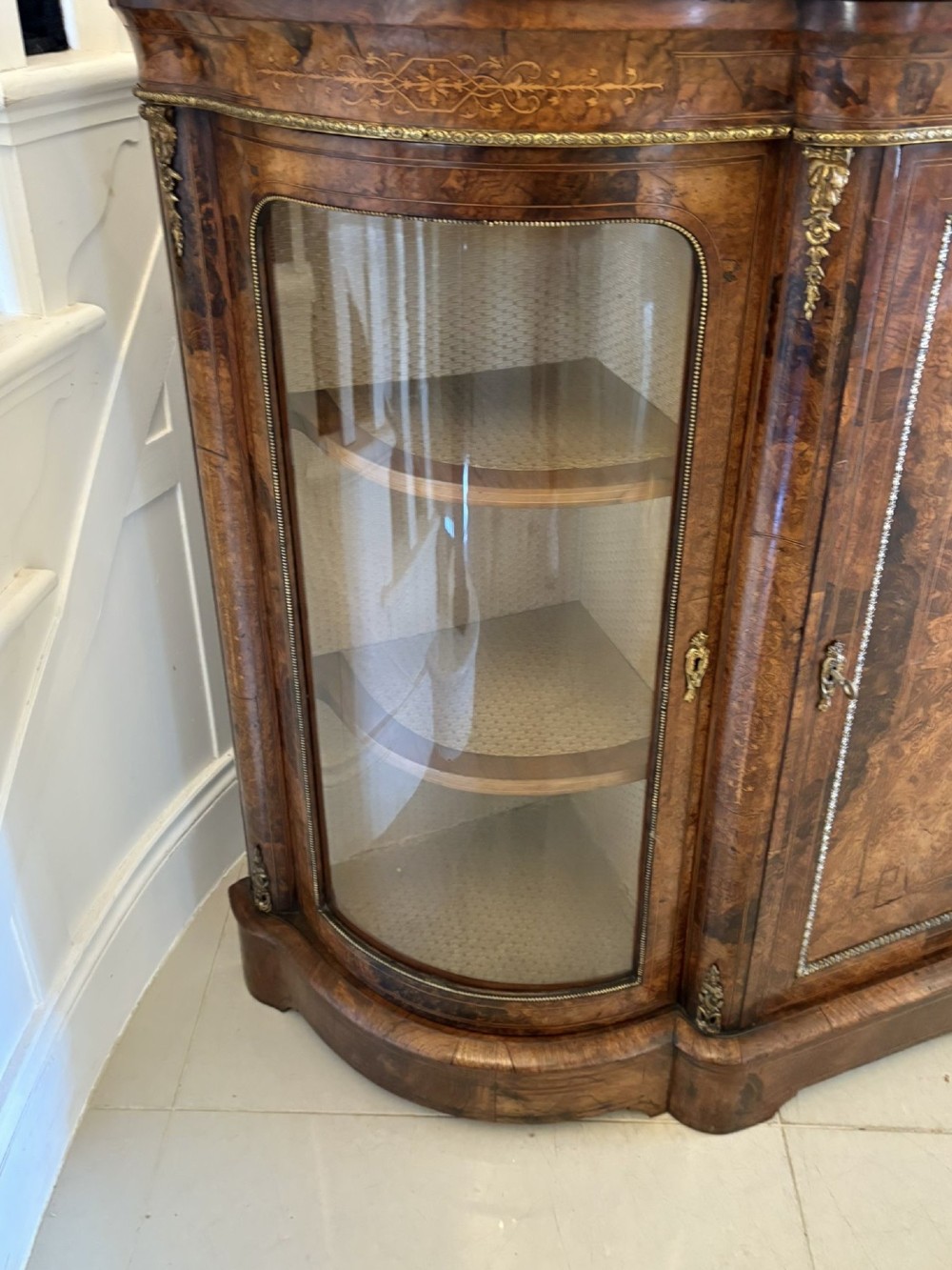 A Victorian burr walnut credenza featuring a central door with a hand-painted porcelain portrait plaque flanked by two curved glass display cupboards and gilt-brass mounts. View X