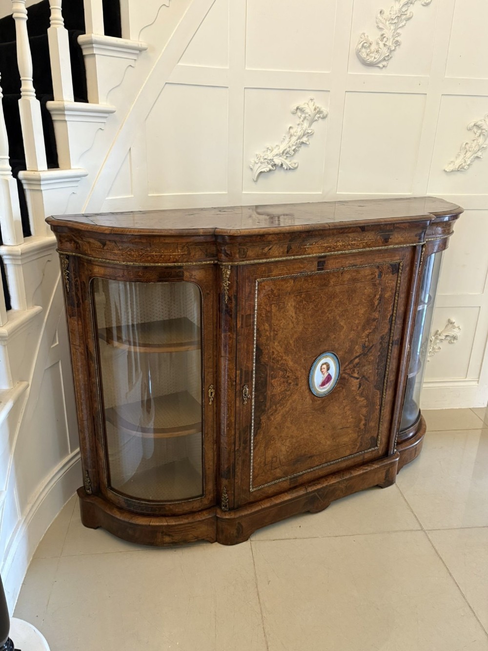 A Victorian burr walnut credenza featuring a central door with a hand-painted porcelain portrait plaque flanked by two curved glass display cupboards and gilt-brass mounts. View XIII