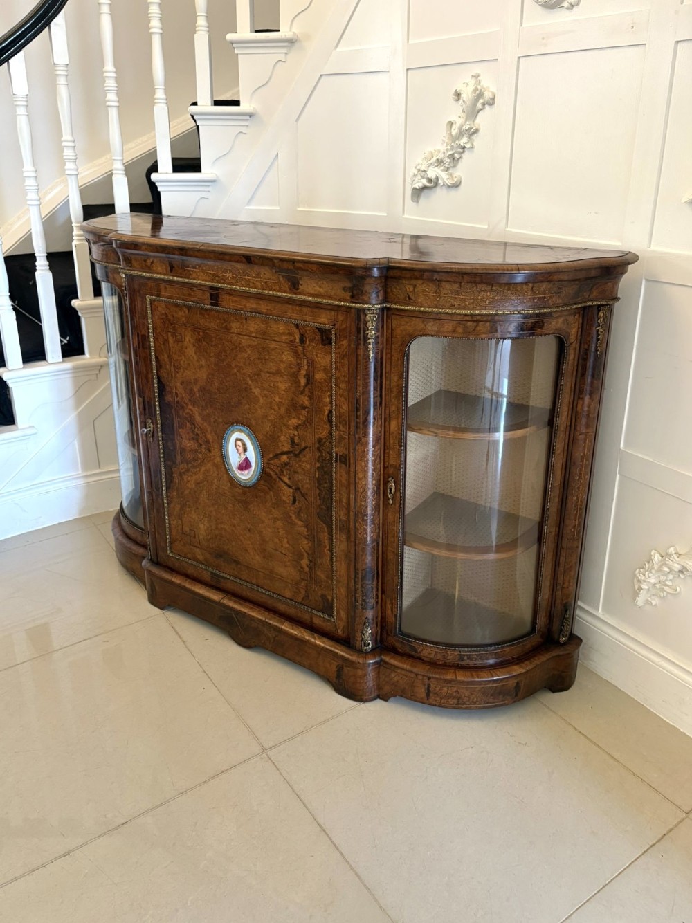 A Victorian burr walnut credenza featuring a central door with a hand-painted porcelain portrait plaque flanked by two curved glass display cupboards and gilt-brass mounts. View XIV