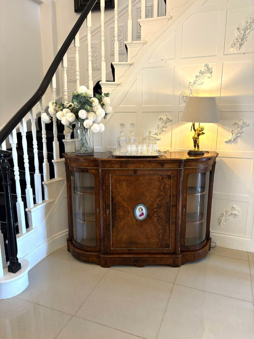 A Victorian burr walnut credenza featuring a central door with a hand-painted porcelain portrait plaque flanked by two curved glass display cupboards and gilt-brass mounts. View XV