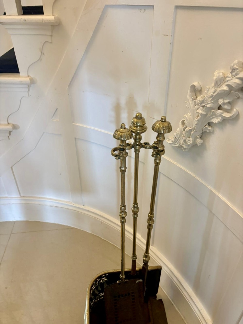 An antique Regency period brass fireplace fender featuring intricate pierced metalwork, claw feet, and matching original brass fire irons positioned at either end. View IV