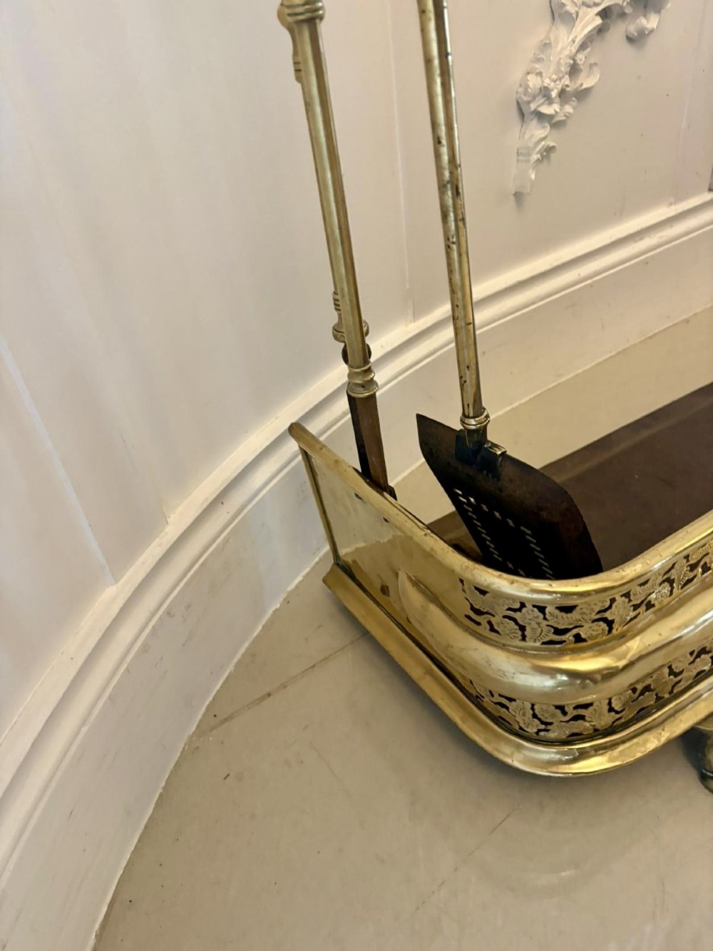 An antique Regency period brass fireplace fender featuring intricate pierced metalwork, claw feet, and matching original brass fire irons positioned at either end. View XI