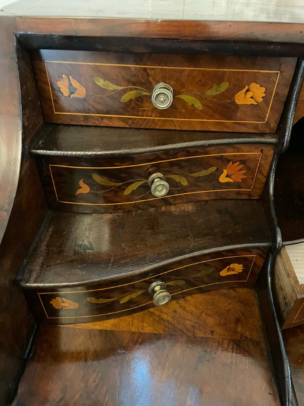 An 18th-century burr walnut bombe bureau featuring floral marquetry inlay, three curved drawers with brass handles, a slant top, and carved feet. View II