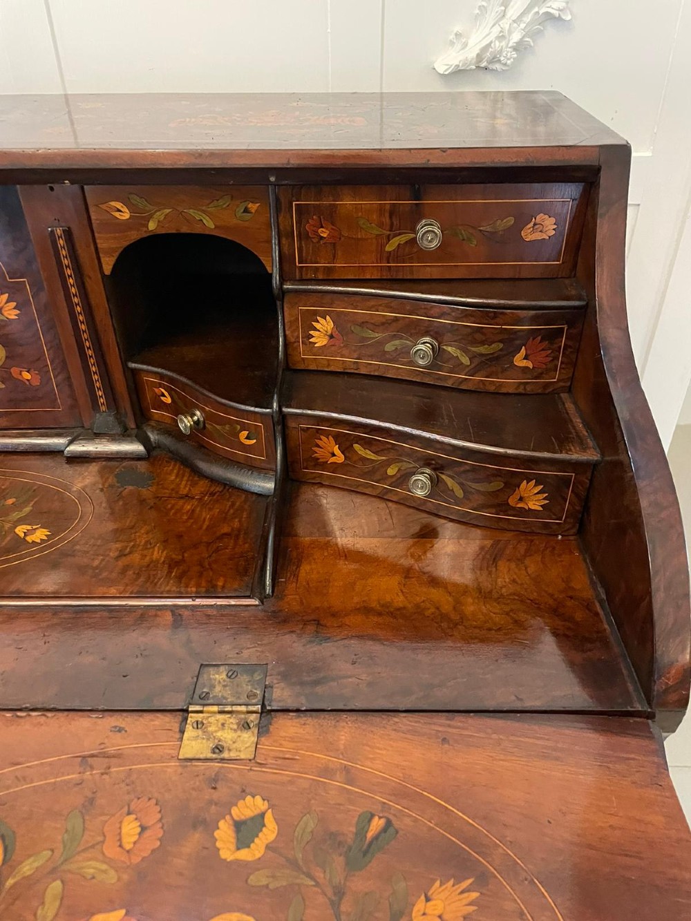 An 18th-century burr walnut bombe bureau featuring floral marquetry inlay, three curved drawers with brass handles, a slant top, and carved feet. View III