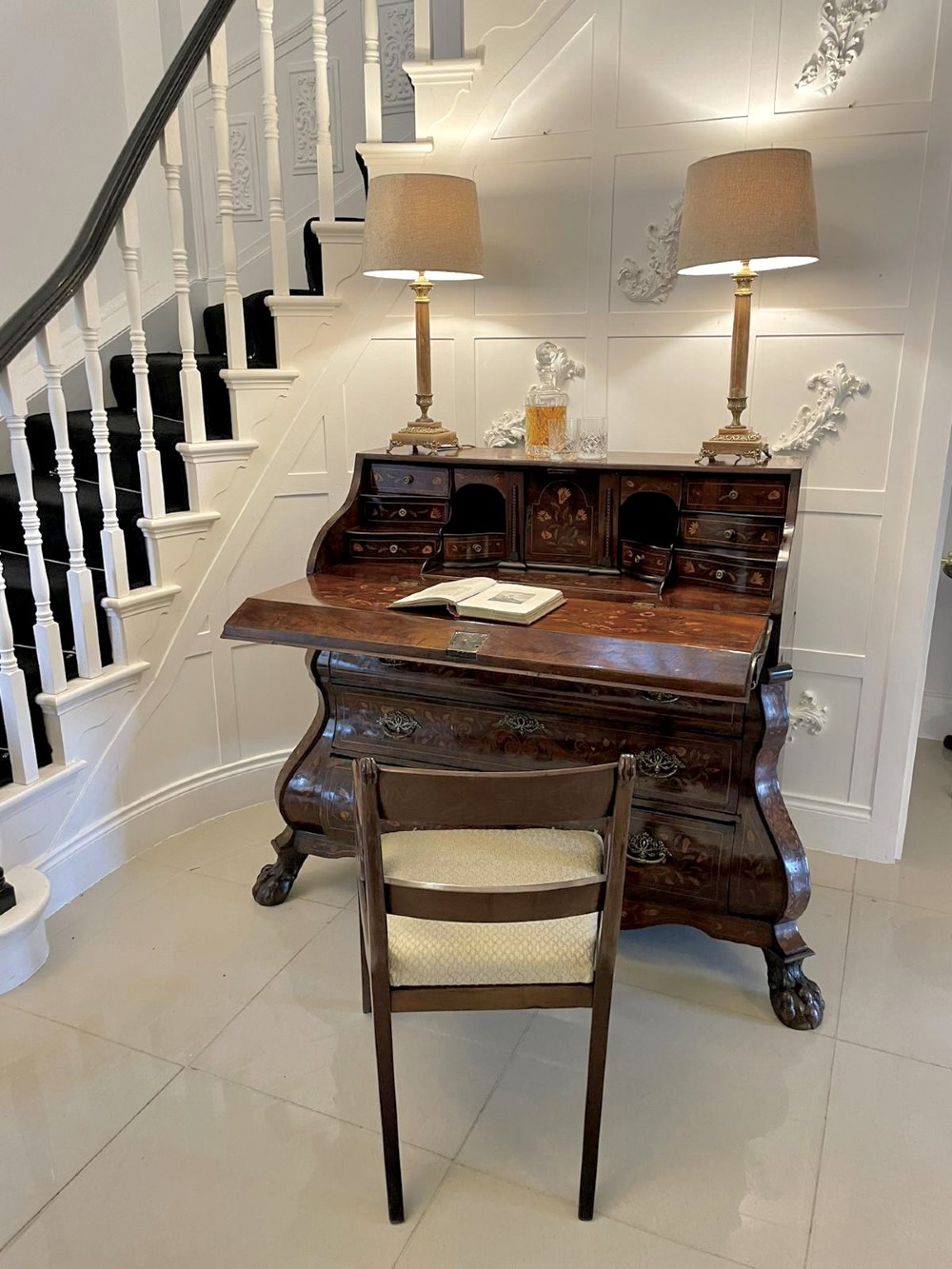 An 18th-century burr walnut bombe bureau featuring floral marquetry inlay, three curved drawers with brass handles, a slant top, and carved feet. View IV