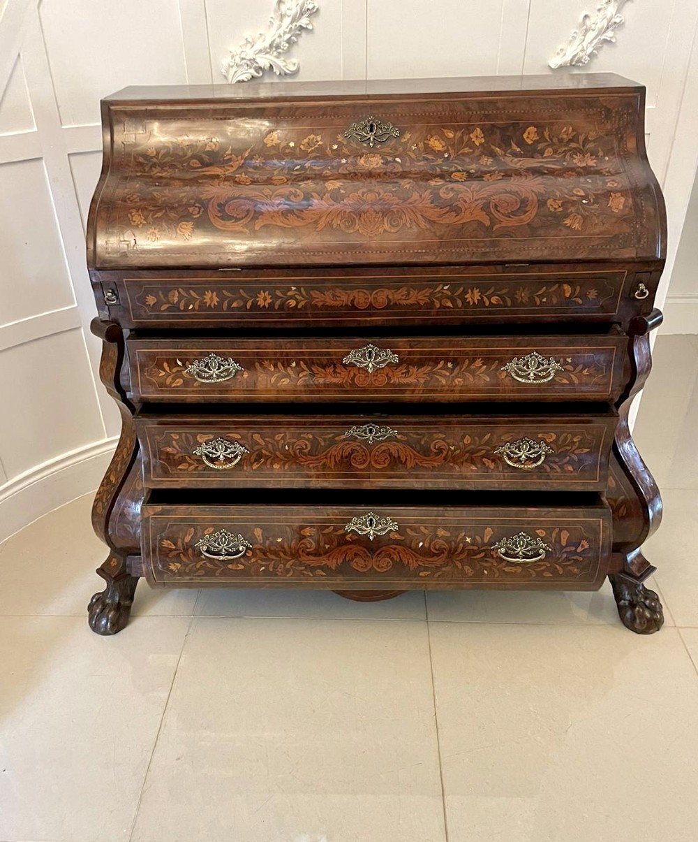 An 18th-century burr walnut bombe bureau featuring floral marquetry inlay, three curved drawers with brass handles, a slant top, and carved feet. View VII