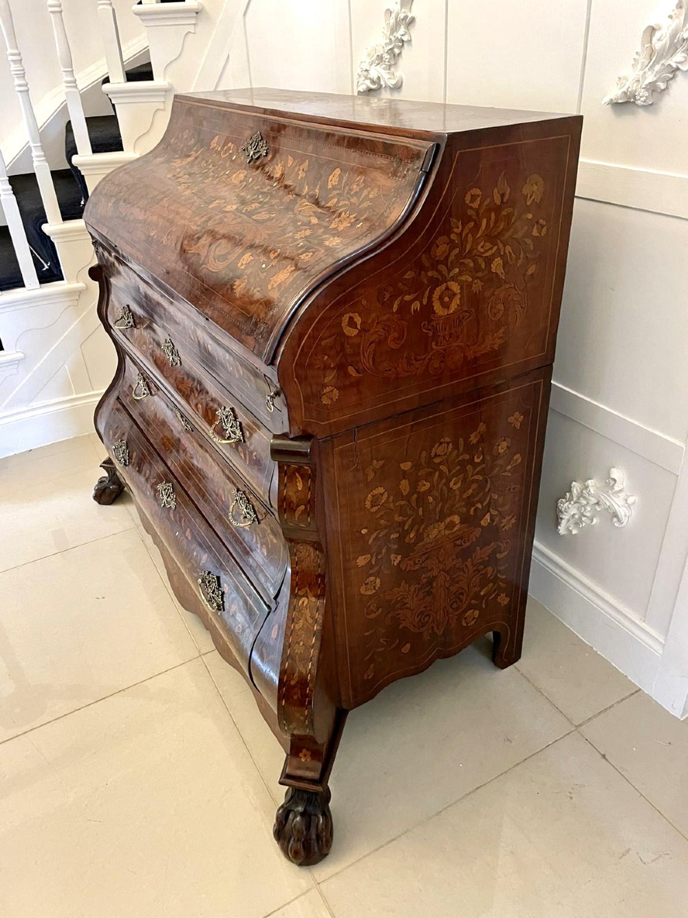 An 18th-century burr walnut bombe bureau featuring floral marquetry inlay, three curved drawers with brass handles, a slant top, and carved feet. View XIII