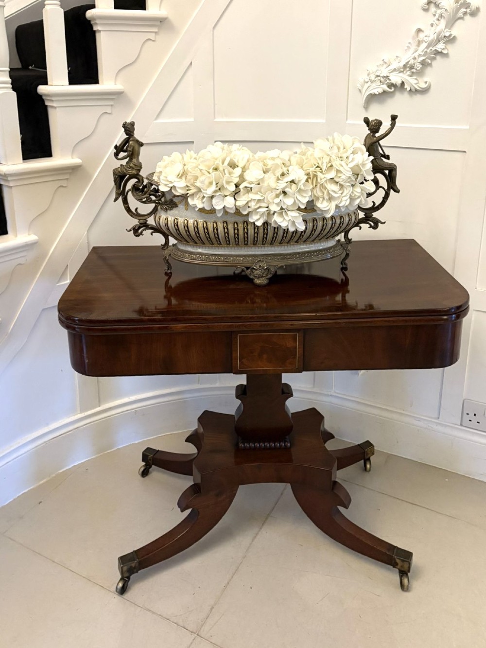 A Regency figured mahogany tea table with a fold-over rectangular top, central pedestal support, and four curved splayed legs on brass castors. View IV