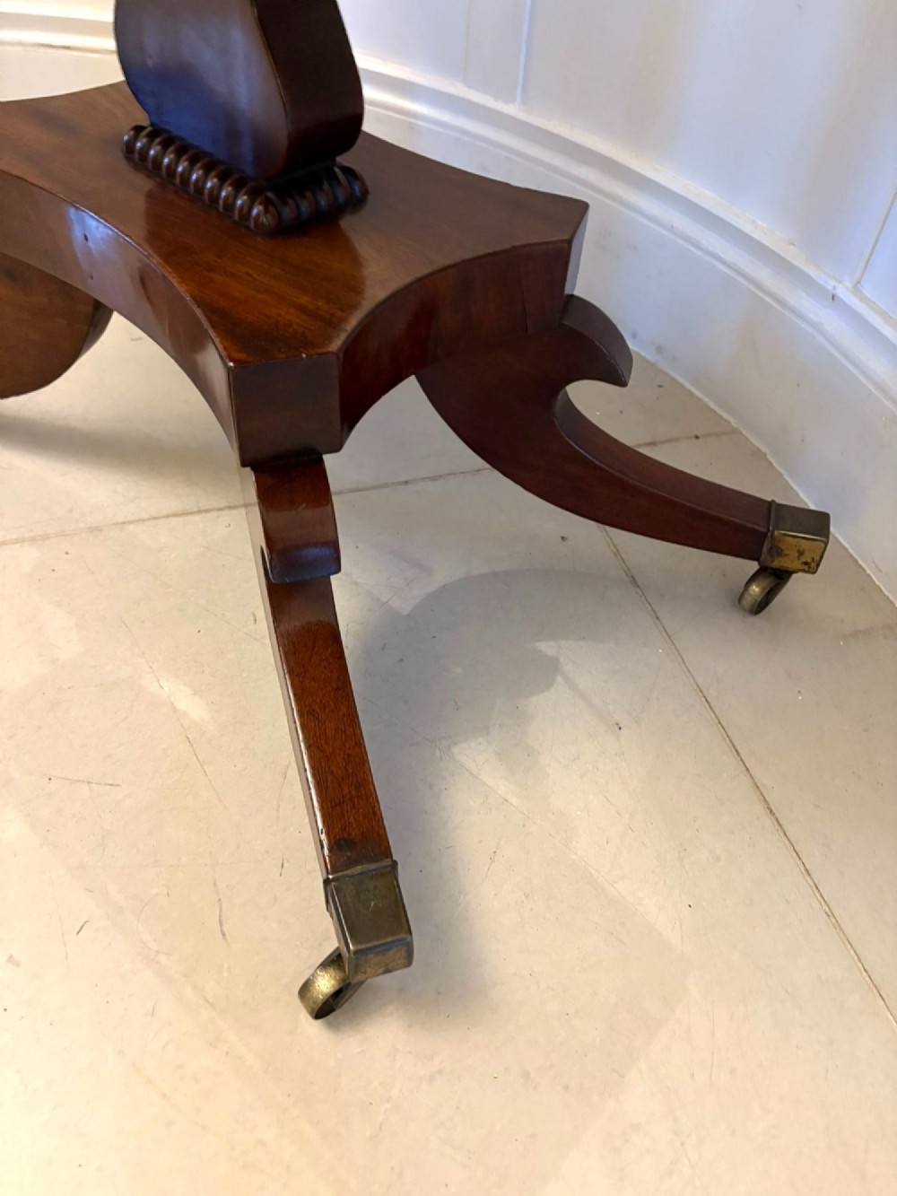 A Regency figured mahogany tea table with a fold-over rectangular top, central pedestal support, and four curved splayed legs on brass castors. View VII